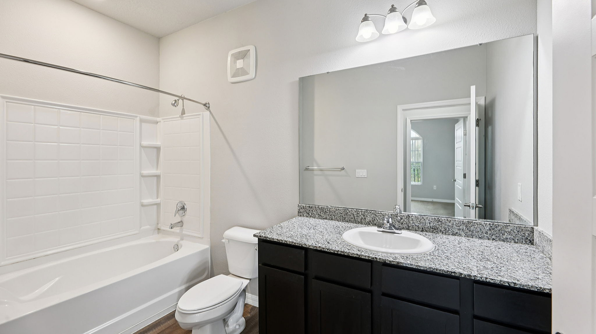 Elegant bathroom with granite countertop, large mirror, and modern lighting fixtures, offering a serene retreat.