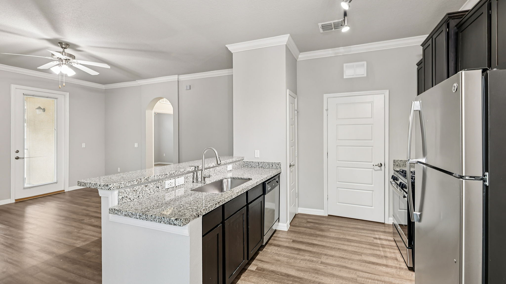 Sleek modern kitchen with granite countertops, stainless steel appliances, and elegant wood flooring in a bright, open-concept space.