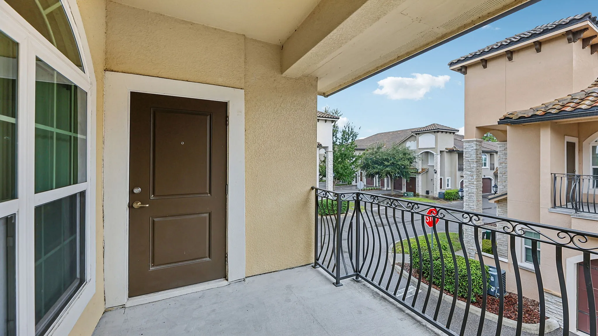 Inviting apartment entrance with elegant wrought-iron railing and charming neighborhood view.