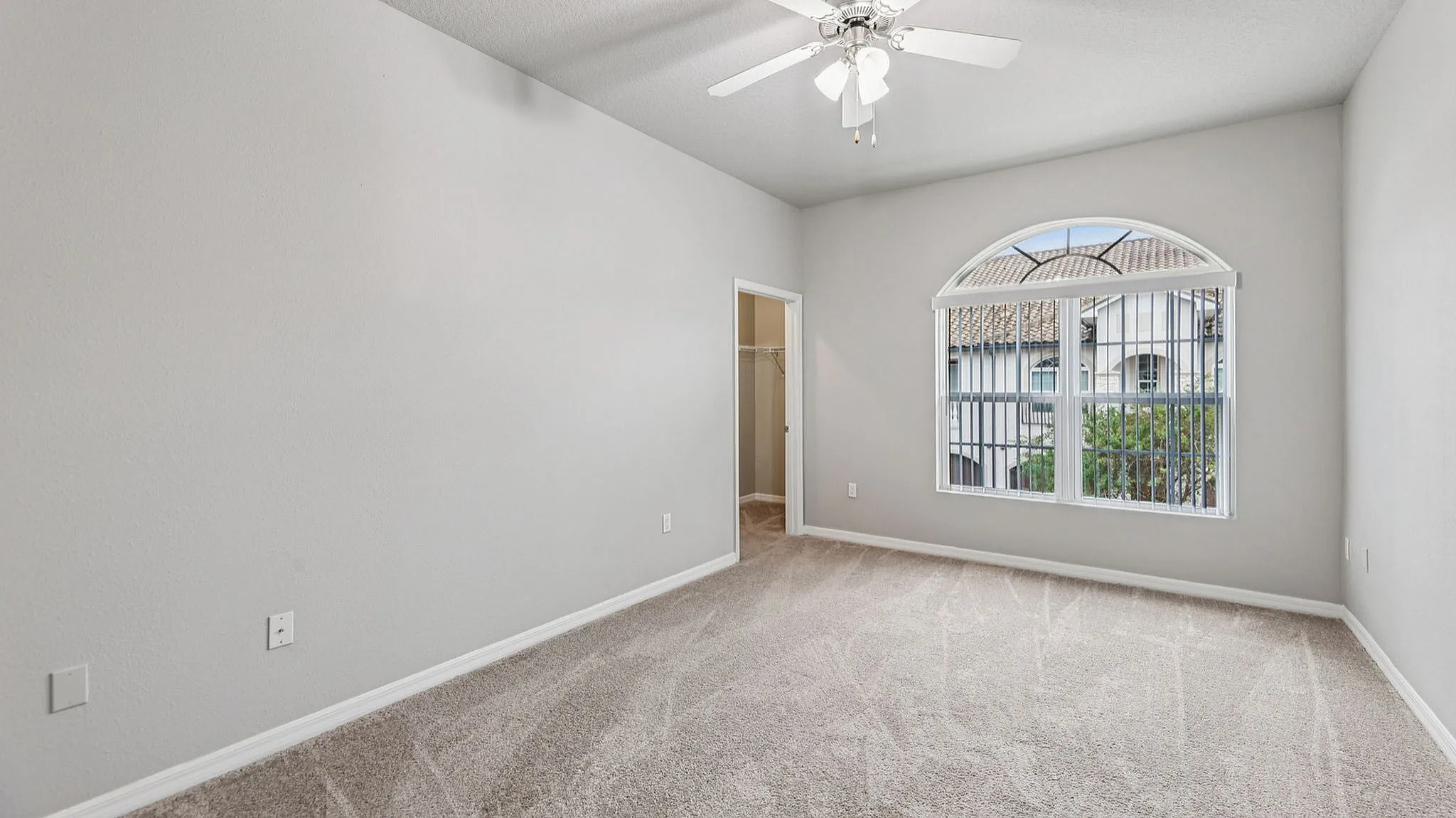 Bright and airy bedroom with plush carpet, large window showcasing scenic views, and a convenient walk-in closet.