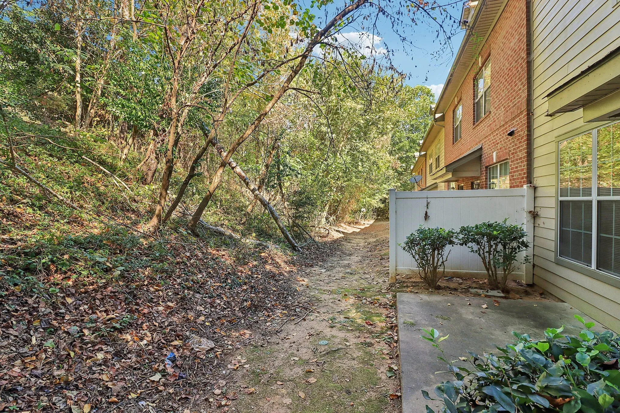 Charming apartment exterior with scenic woodland view, featuring a cozy patio and lush greenery for a serene living experience.