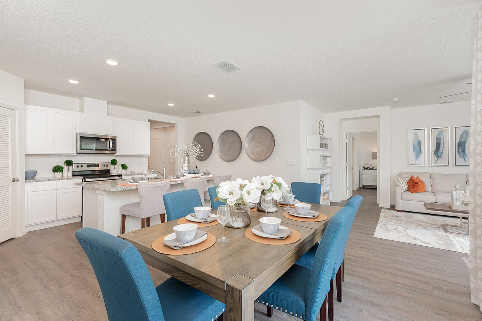 Chic open-plan living area with a modern kitchen, elegant dining setup, and inviting living room. Features vibrant blue chairs and tasteful decor.