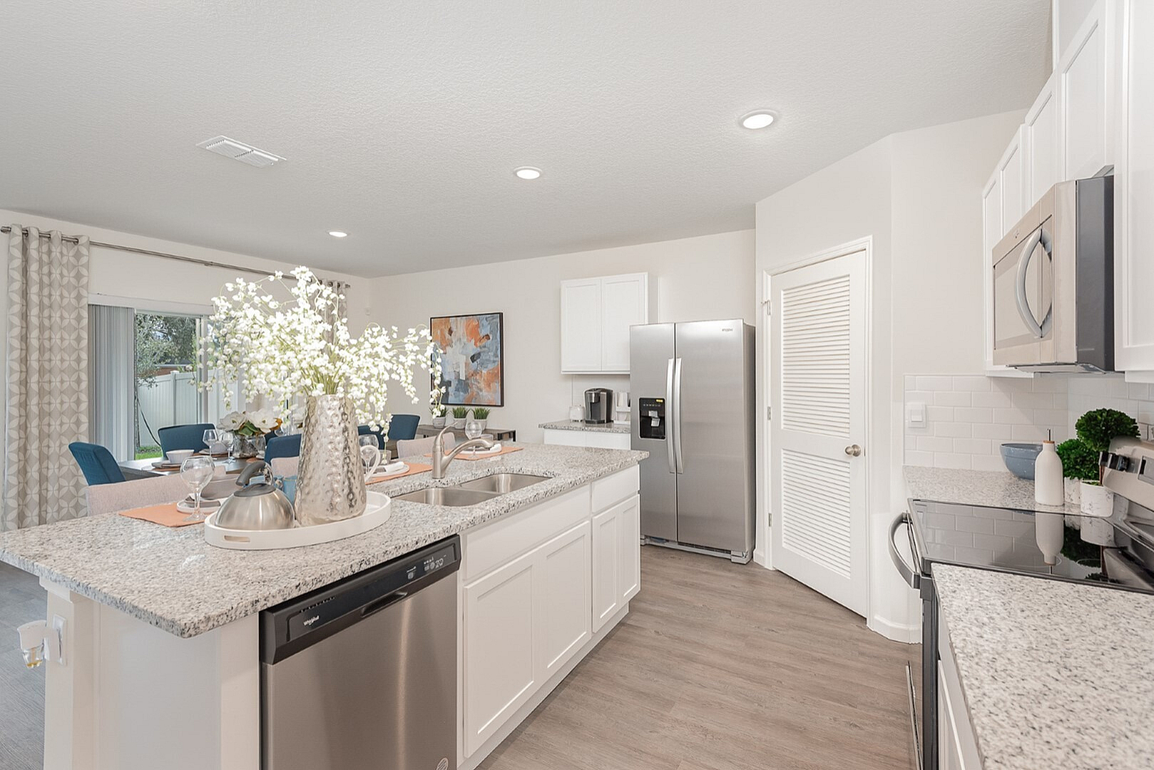 Bright and modern kitchen with sleek granite countertops, stainless steel appliances, and an elegant dining area in a stylish open-concept layout.