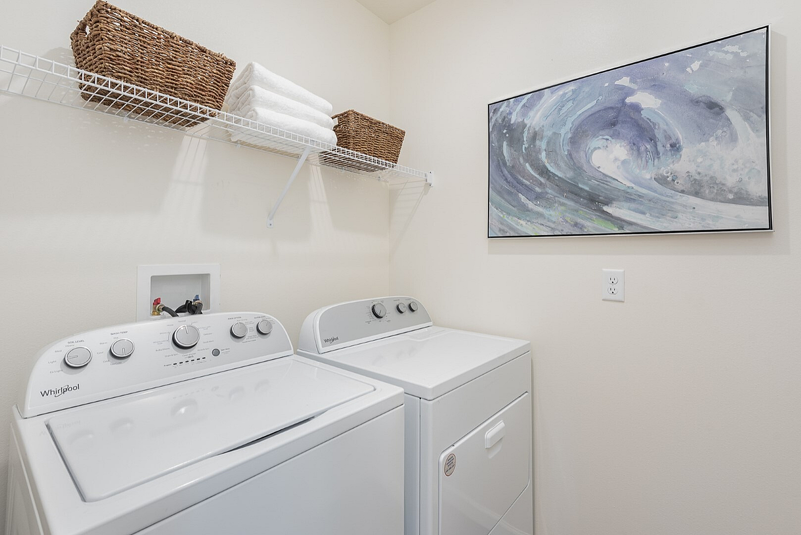 Modern laundry room with sleek appliances, elegant wall art, and convenient shelving.