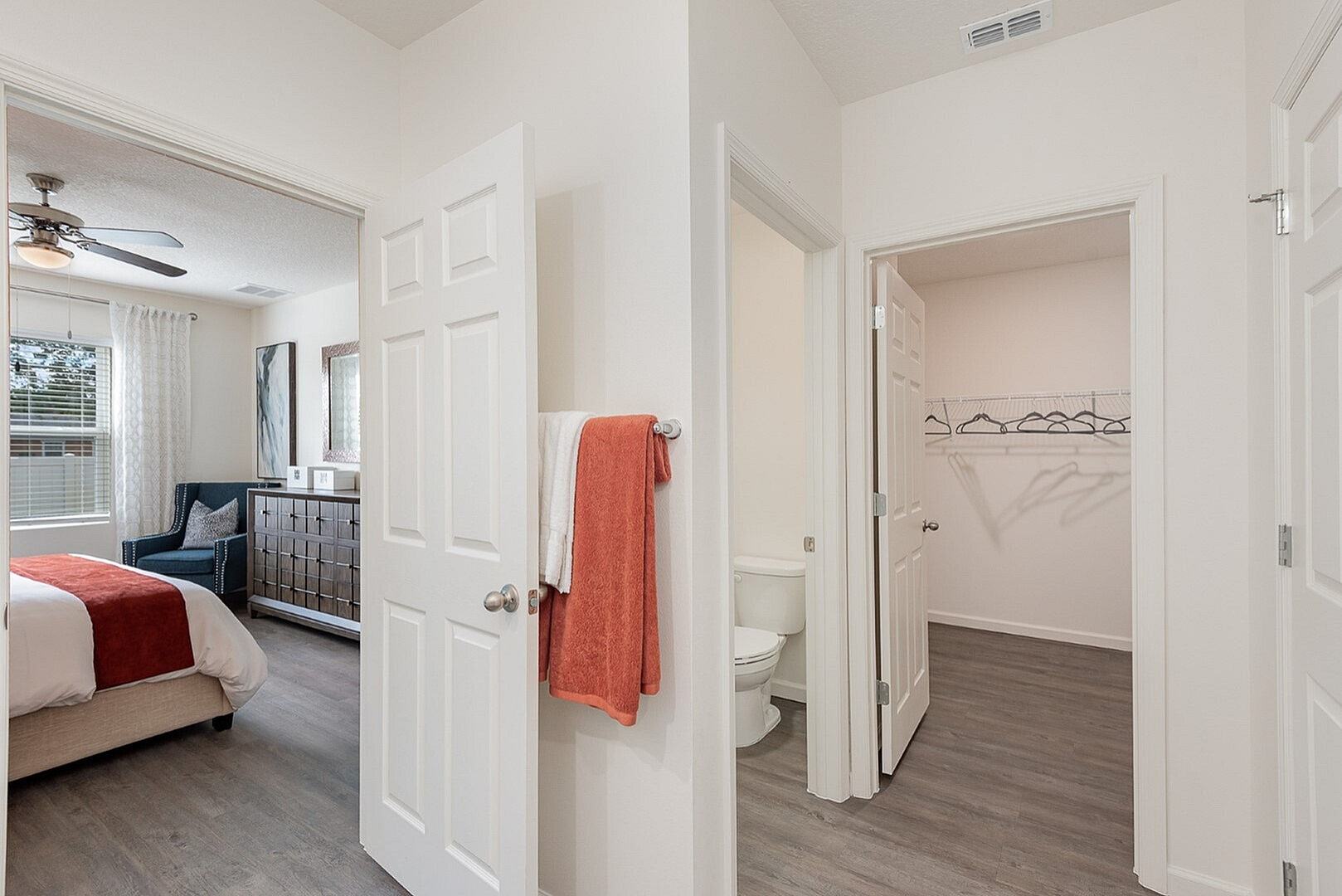 Modern apartment hallway with access to a bright bedroom, sleek bathroom, and spacious walk-in closet, highlighting chic decor and elegant flooring.