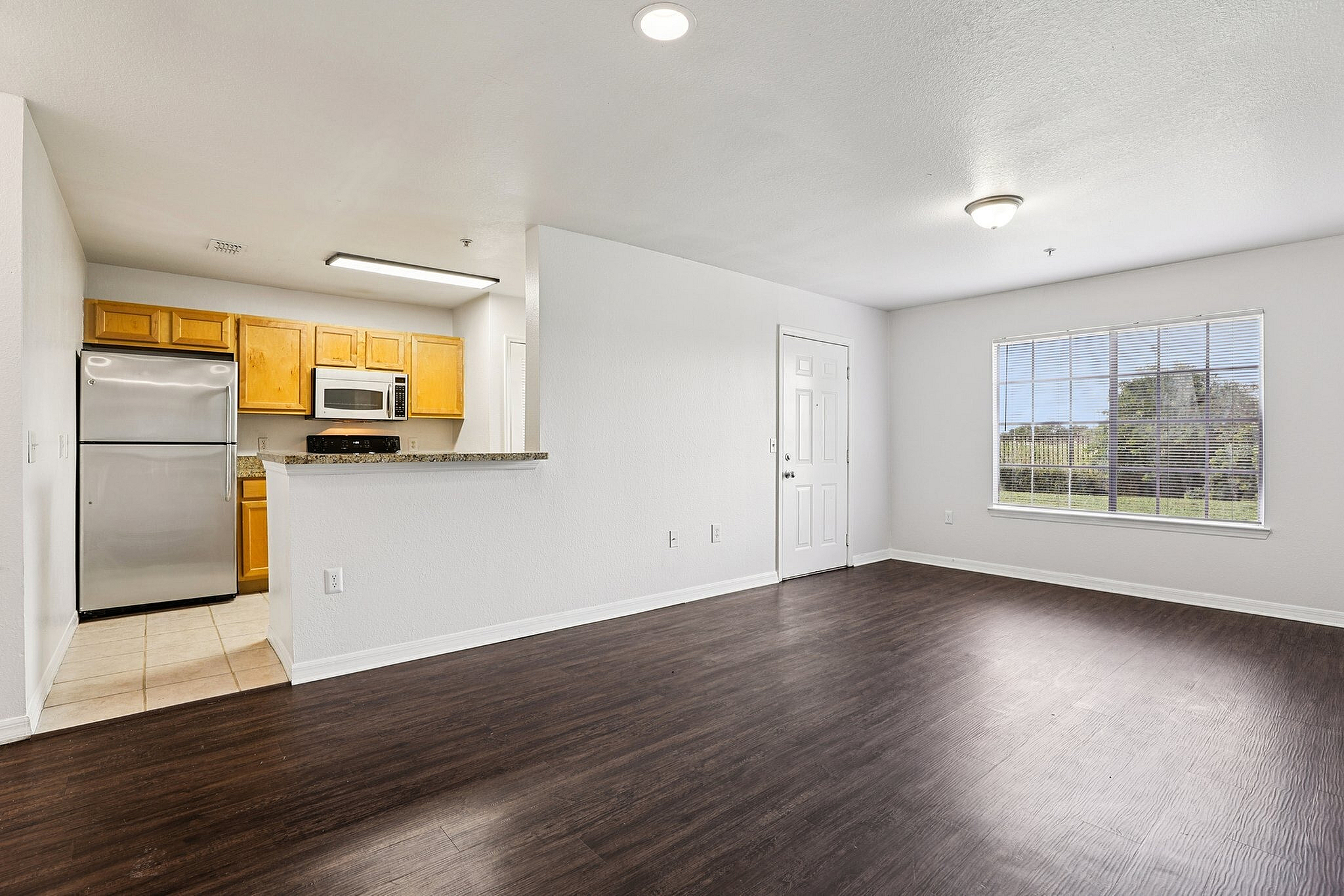 Contemporary apartment with open-concept living area featuring sleek hardwood floors and a modern kitchen with stainless steel appliances.