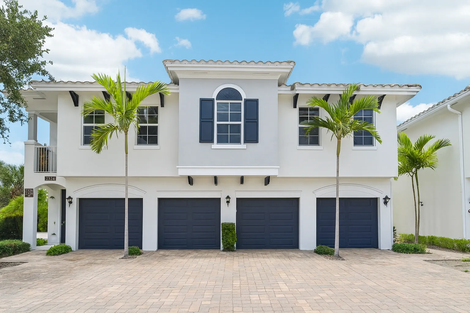 Charming Mediterranean architecture, featuring a tiled roof and vibrant palm trees, offering spacious two-car garages.
