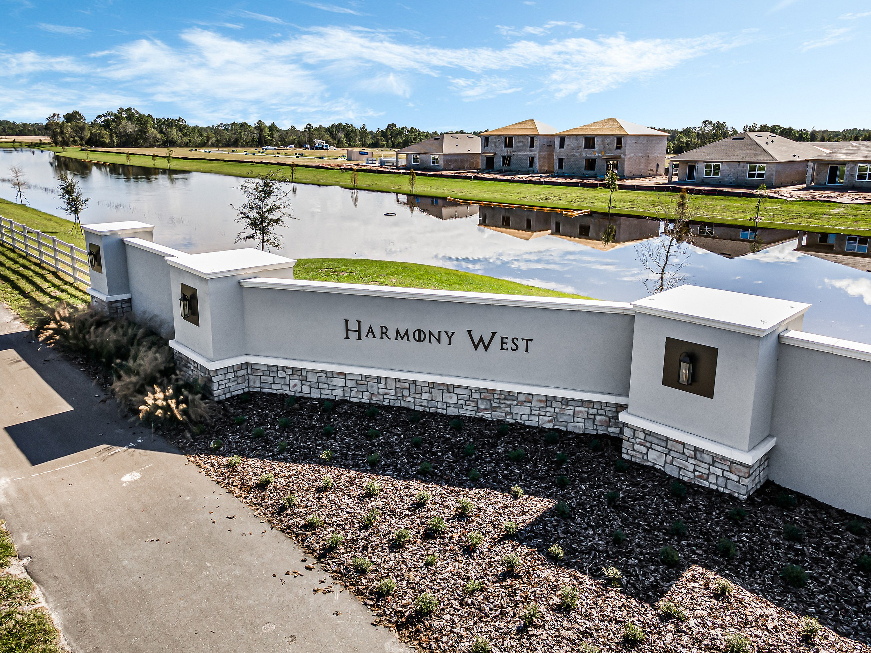 Serene lakeside view of Harmony West community with modern homes and lush greenery.