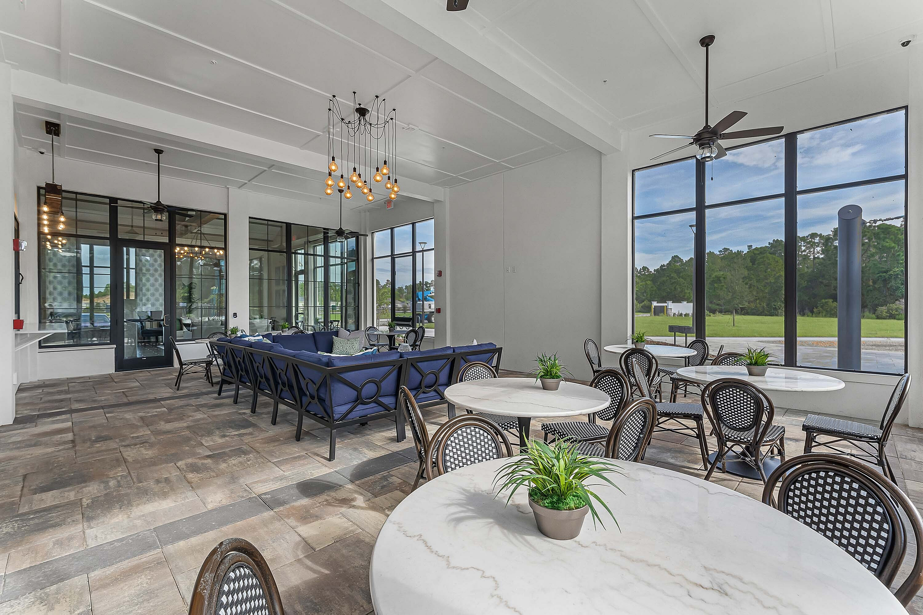 Elegant community lounge with chic seating, expansive windows, and lush outdoor views.