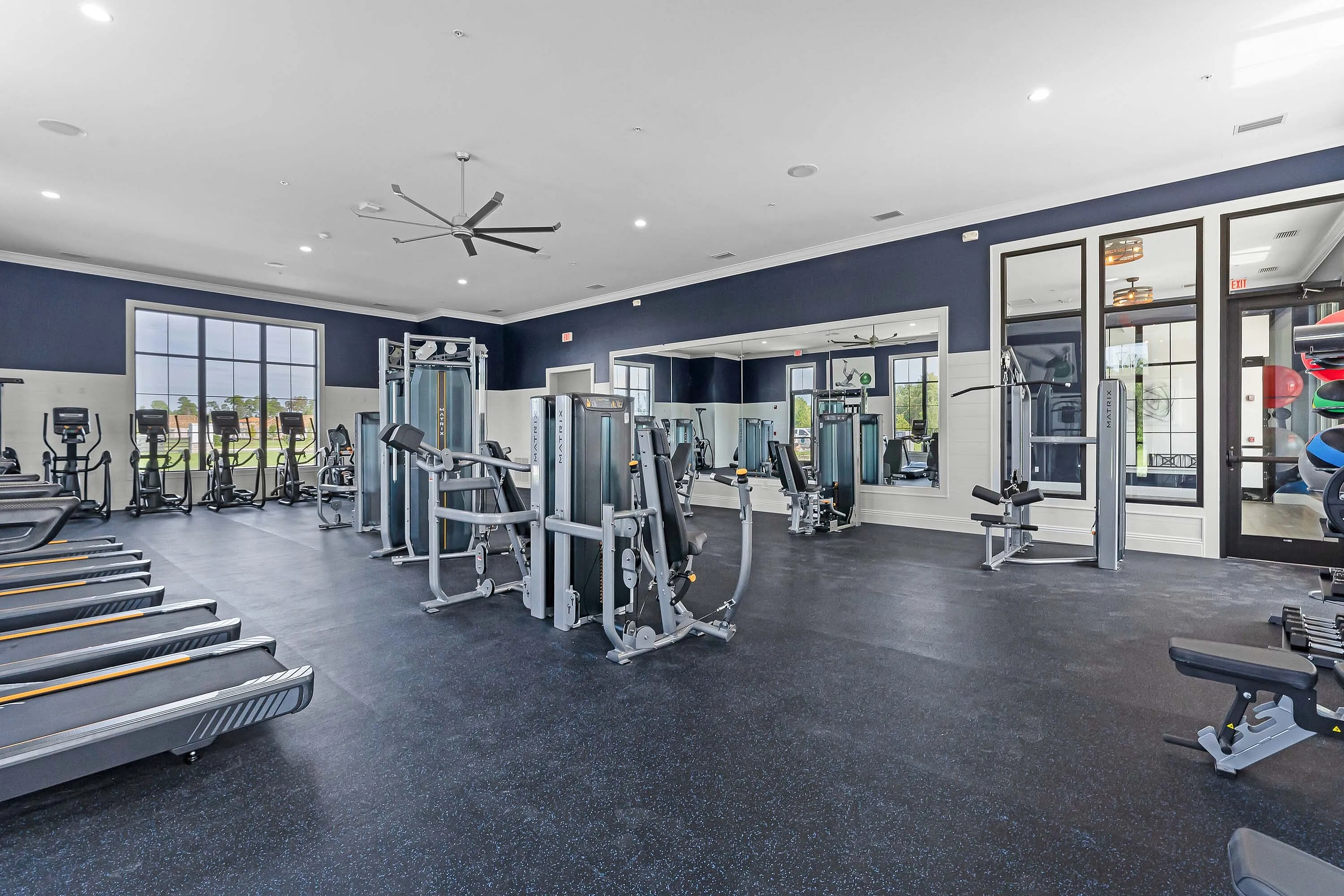 Modern fitness center featuring state-of-the-art cardio equipment, weight machines, and ample natural light.