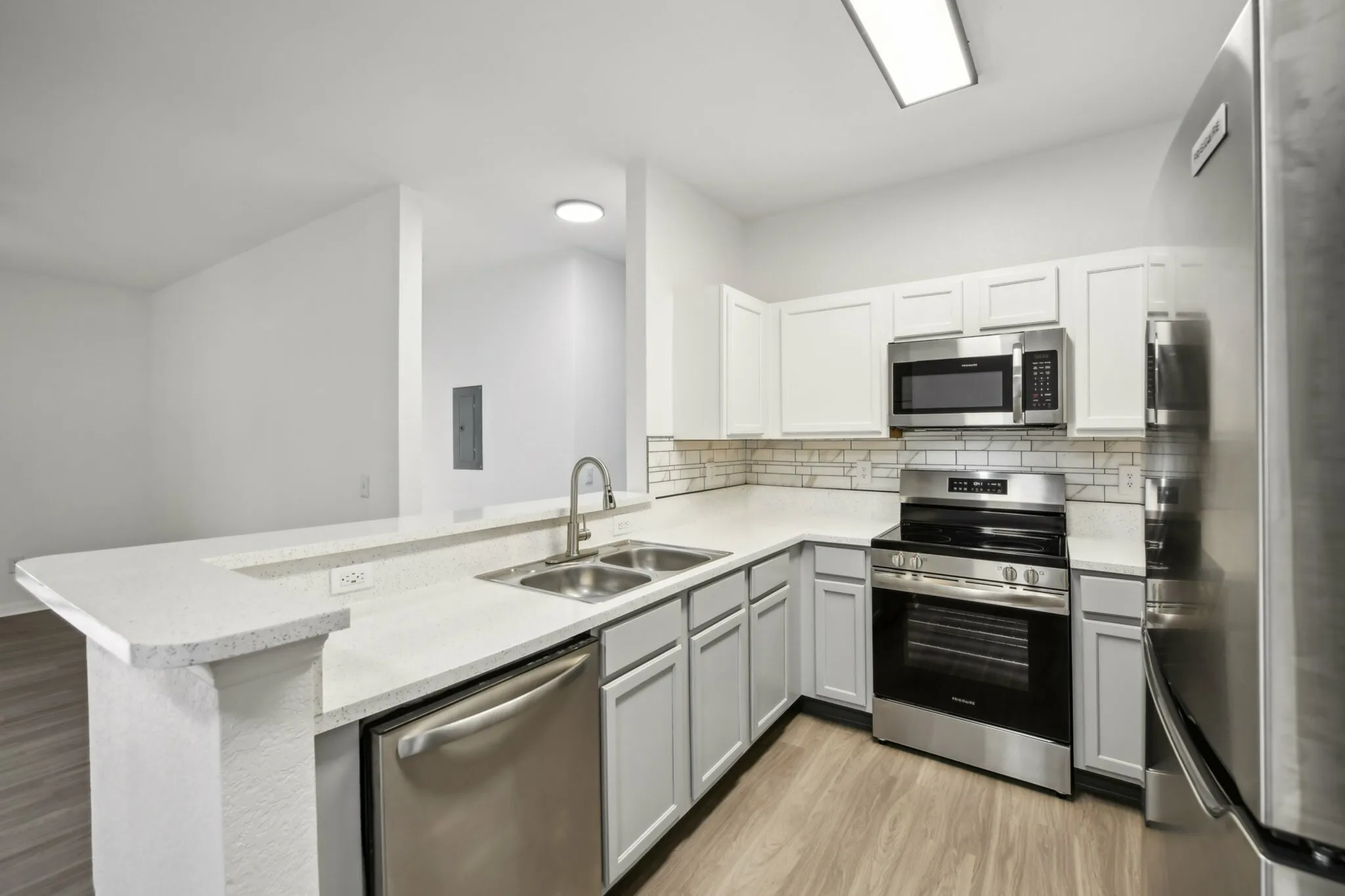 interior pic of deluxe kitchen unit with gray planking and white walls, stainless steel appliances and backsplash