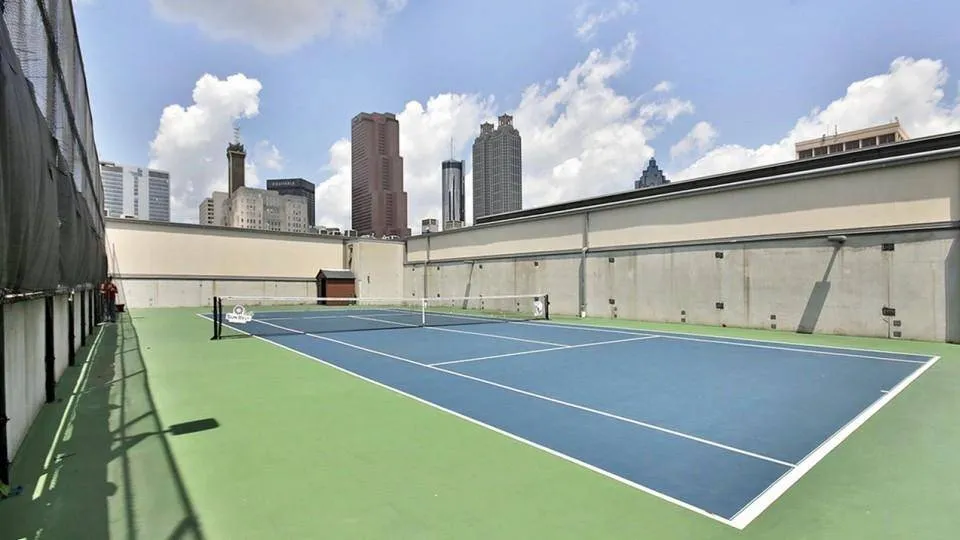 sunny day of tennis court on rooftop surrounded by walls