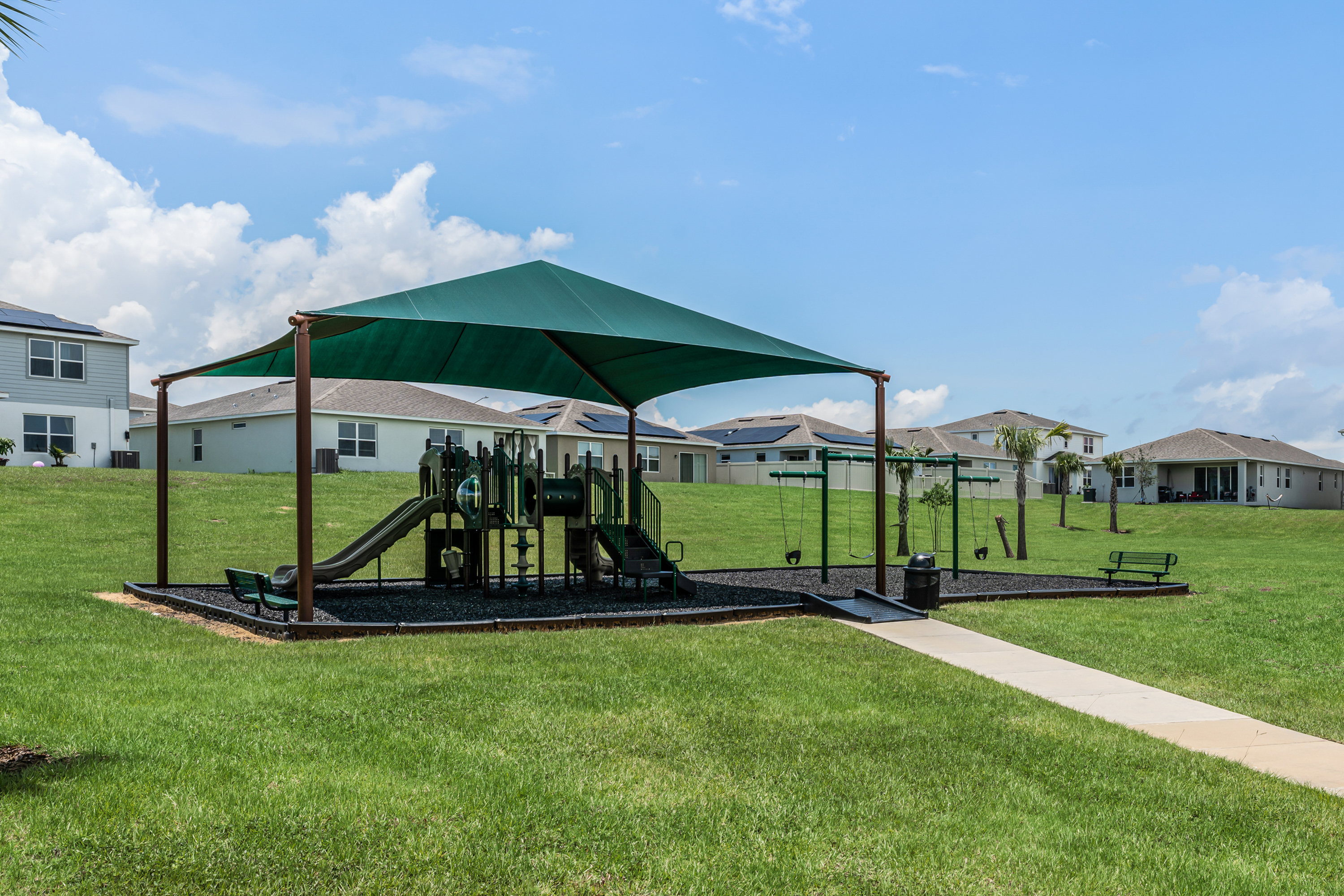 playground area on a sunny day includes slide swings and seating area