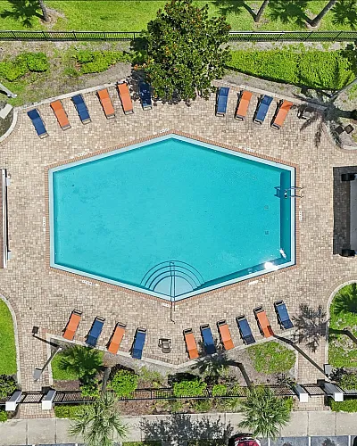 Luxurious aerial view of a hexagonal swimming pool with stylish sun loungers and lush green surroundings, perfect for relaxation and leisure.