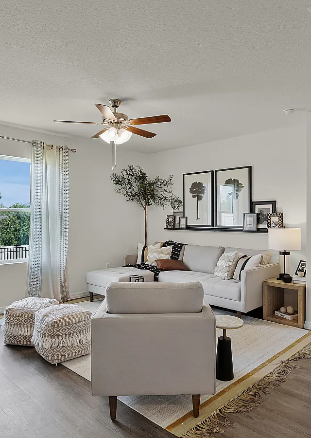 Bright and inviting living room with elegant decor, cozy seating, and large window offering lush views, adjacent to a modern bedroom.