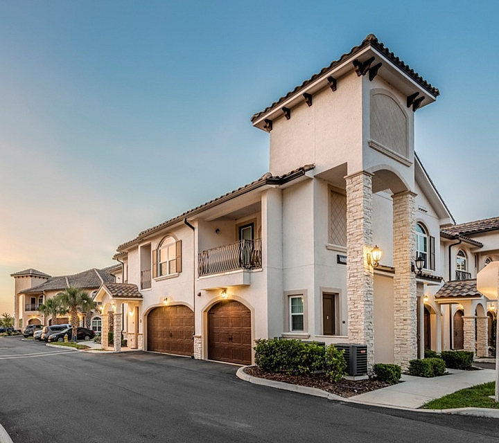 Charming Mediterranean-style apartment complex with stone accents, elegant balconies, and warm lighting at sunset.