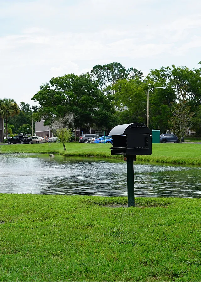 Charming apartment community with a peaceful pond, fountain, picnic tables, and lush greenery for outdoor relaxation.