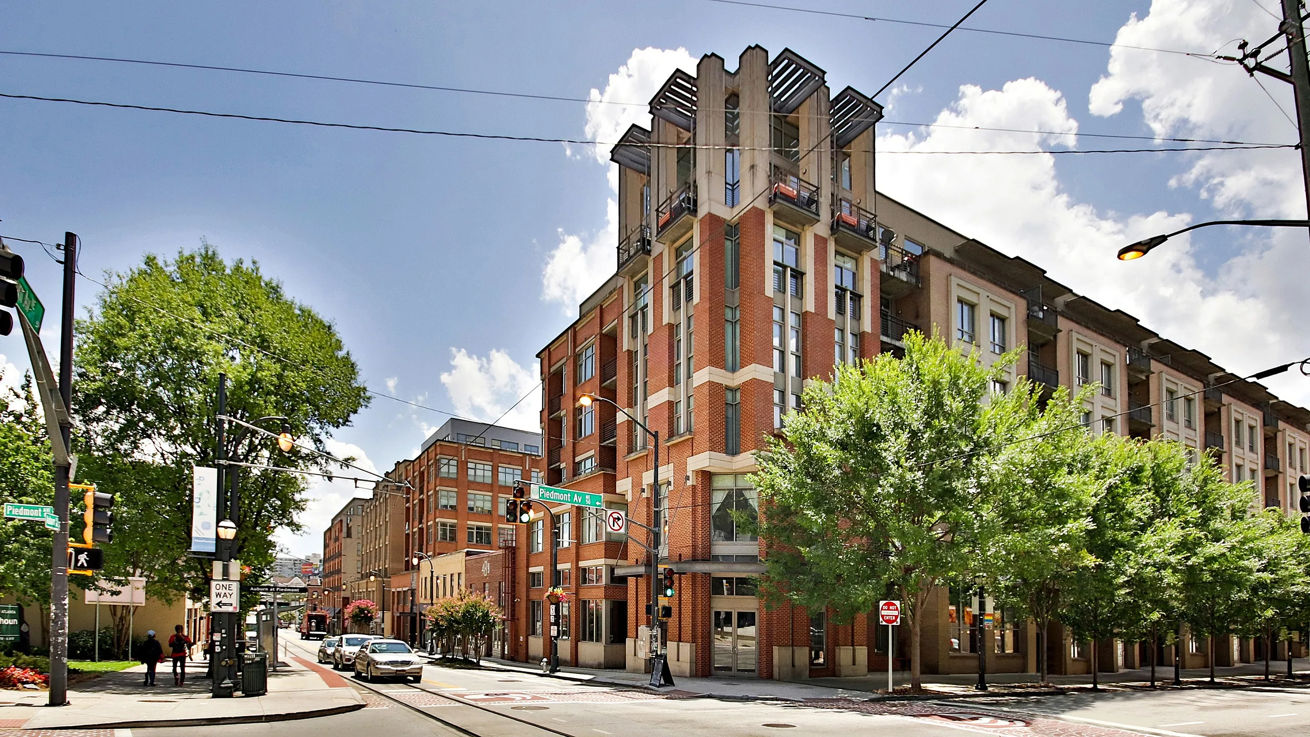 Charming multi-story brick apartment building nestled on a tree-lined street corner, offering urban living with modern architectural flair.