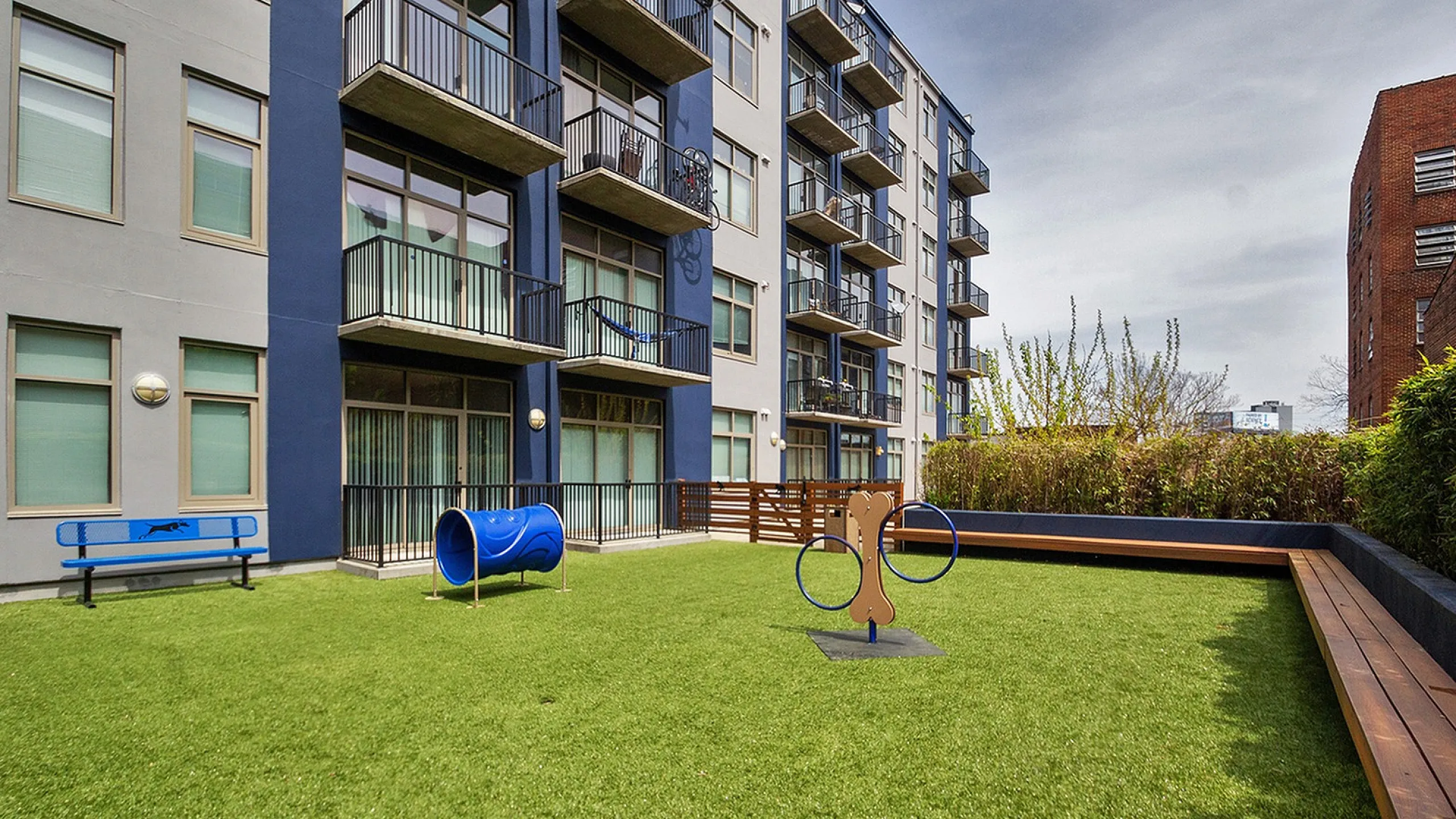 Contemporary apartment complex with lush green outdoor play area, providing a serene and playful environment.