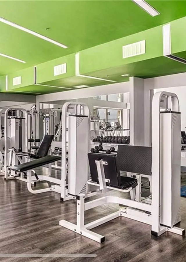 Modern fitness center with green accents, featuring state-of-the-art exercise equipment and natural light.