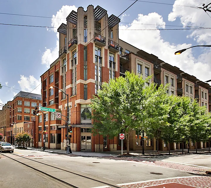 Charming urban apartment building with modern architecture and lush greenery lining the sidewalk, perfect for city living.