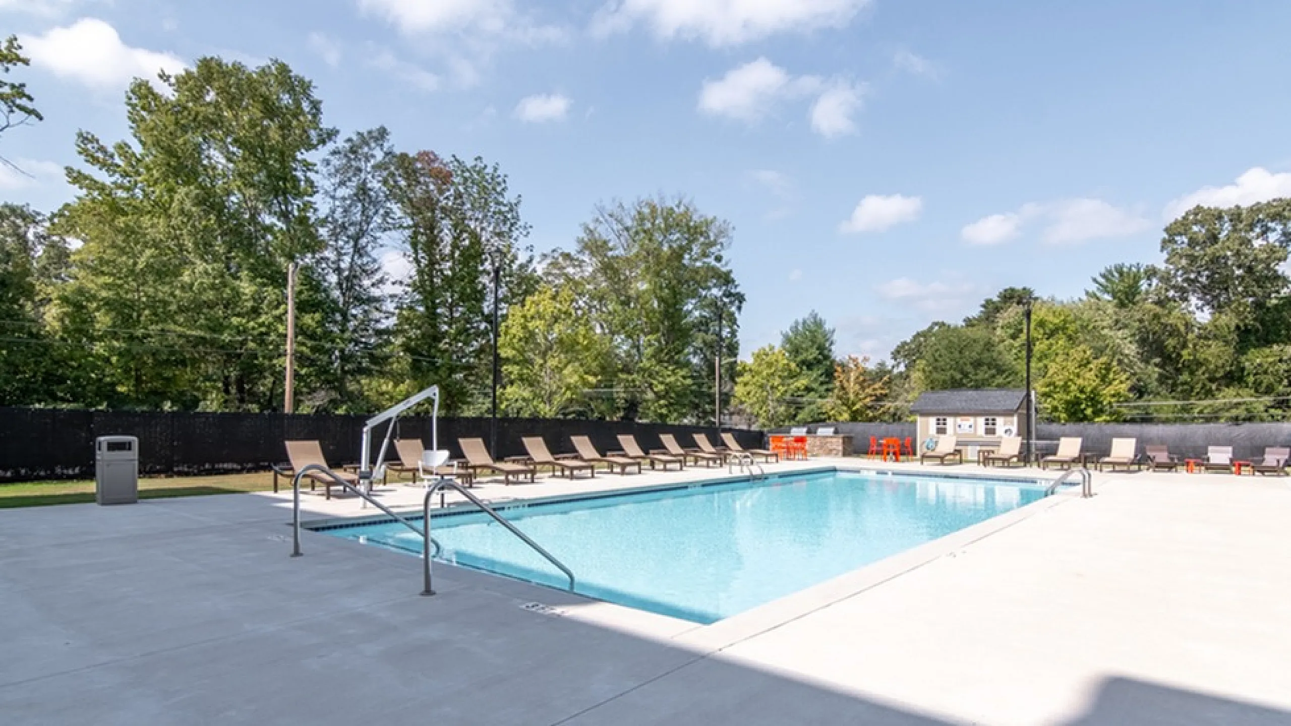 Inviting outdoor pool area with elegant lounge chairs, surrounded by lush greenery for a serene escape.