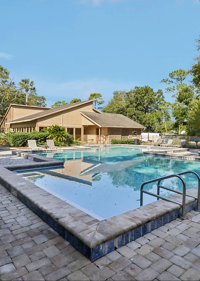 Inviting outdoor pool area with elegant deck chairs, surrounded by lush greenery and a charming wooden gazebo.