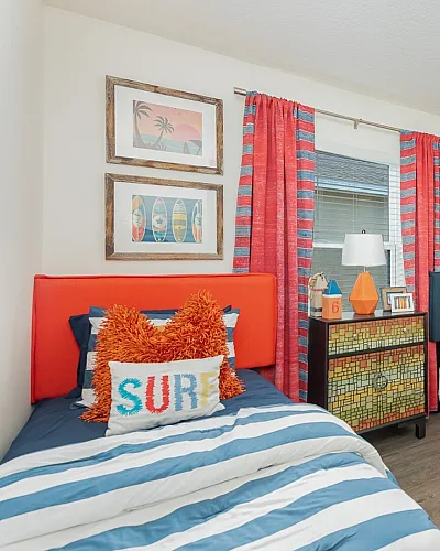 Vibrant coastal-themed kids' bedroom featuring surfboard wall decor, striped bedding, and colorful accents for a playful atmosphere.