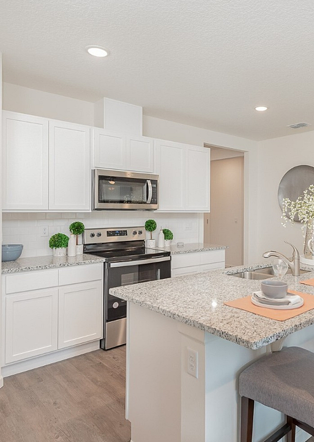 Elegant modern kitchen with granite countertops, sleek white cabinetry, and a cozy breakfast bar adorned with stylish decor.