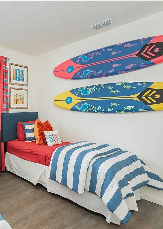 Playful bedroom adorned with vibrant surf-themed decor, featuring two cozy twin beds and colorful striped bedding, perfect for a beach-inspired retreat.