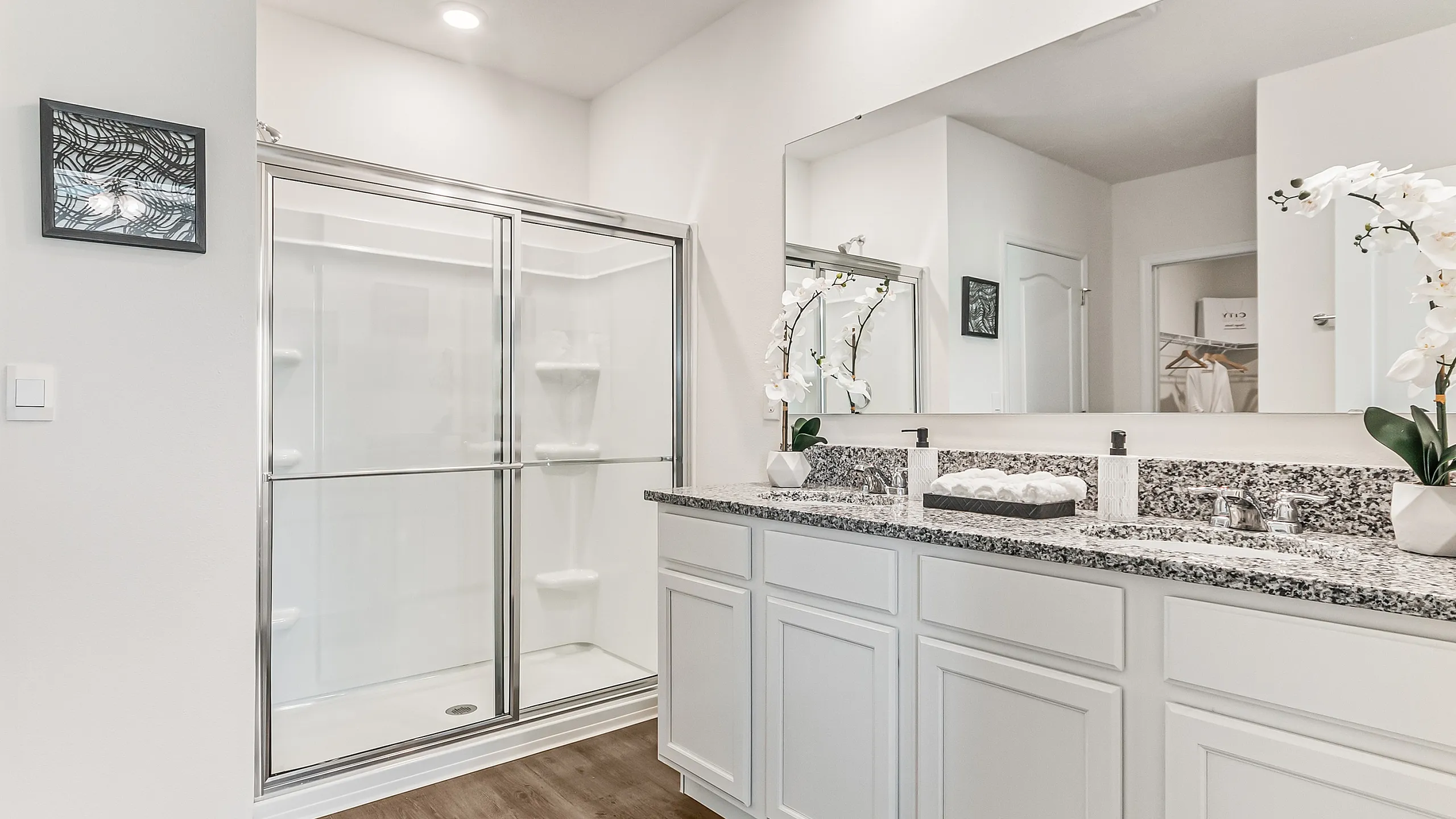 Elegant bathroom with a spacious glass shower, double vanity with granite countertops, and modern accents for a luxurious feel.