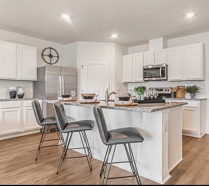 Modern kitchen showcasing sleek white cabinetry, granite countertops, and elegant bar seating in a spacious open floor plan.