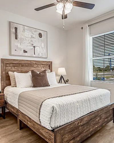 Chic and cozy bedroom featuring a wooden bed frame, elegant bedding, modern nightstands with lamps, and a large window offering natural light.
