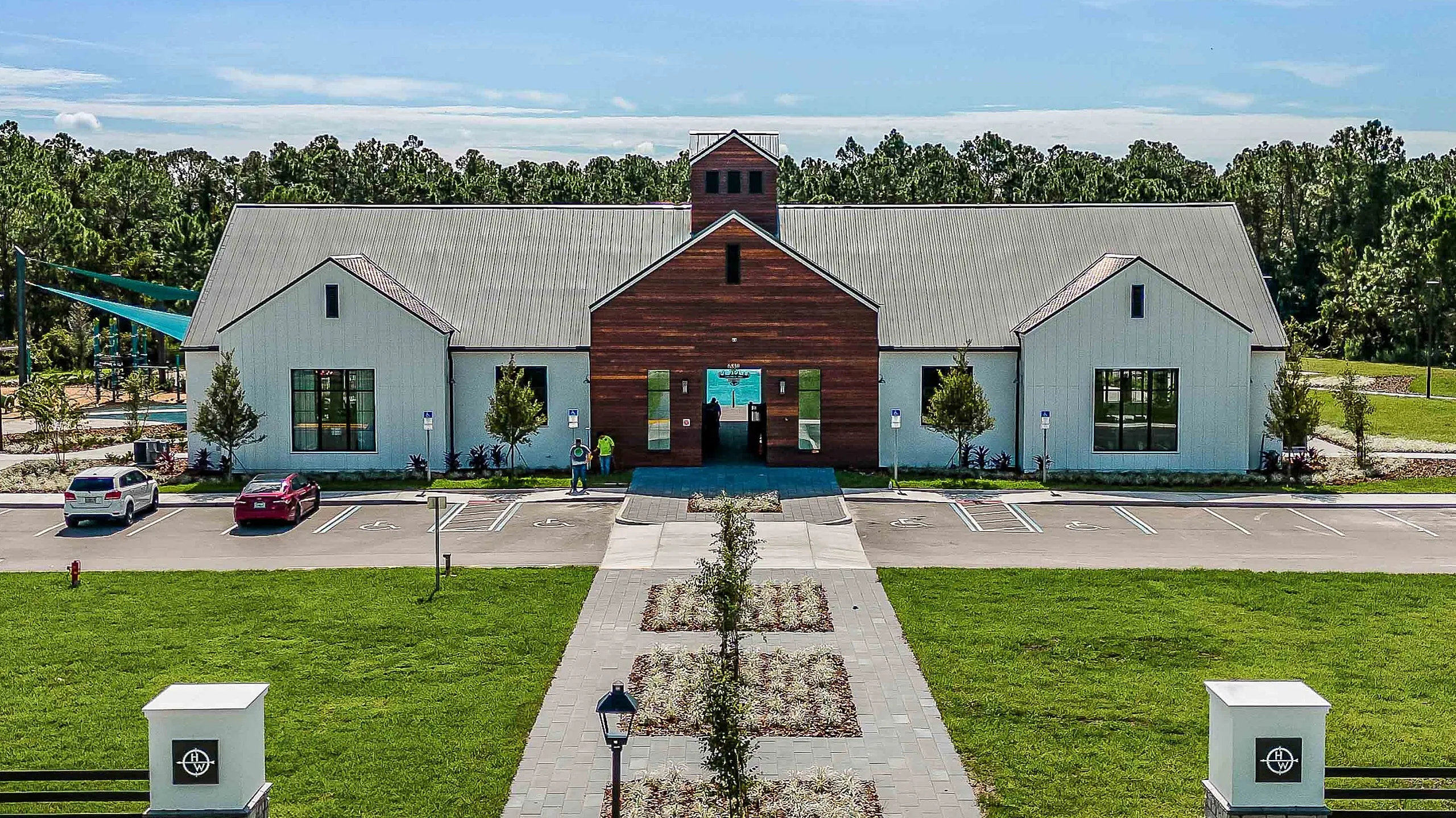 Charming modern building with wooden accents, surrounded by lush greenery and ample parking space, ideal for a community hub.