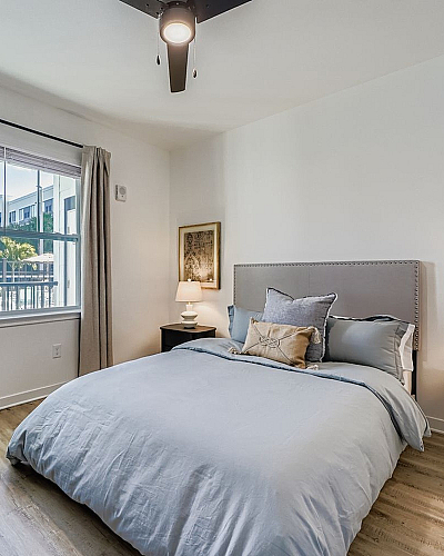 Bright and inviting bedroom with large windows, cozy decor, and modern furnishings.