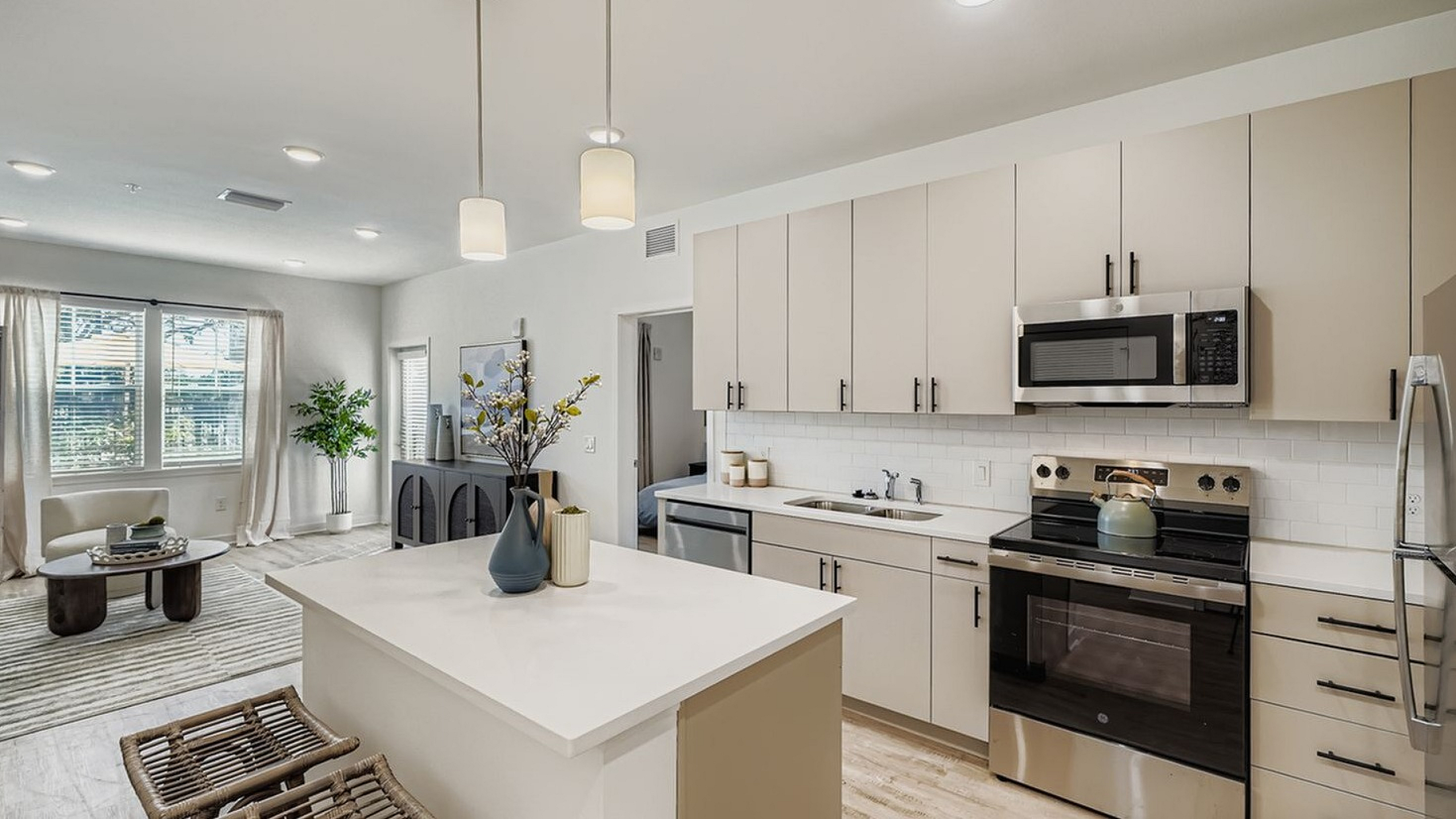 Bright and modern kitchen design with sleek cabinetry, stainless steel appliances, and an inviting open layout connecting to a sunlit living area.