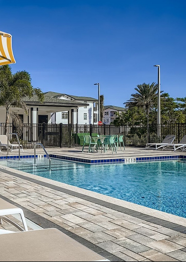 Luxurious outdoor pool area with stylish lounge chairs and vibrant yellow-striped umbrellas, perfect for relaxation and leisure.