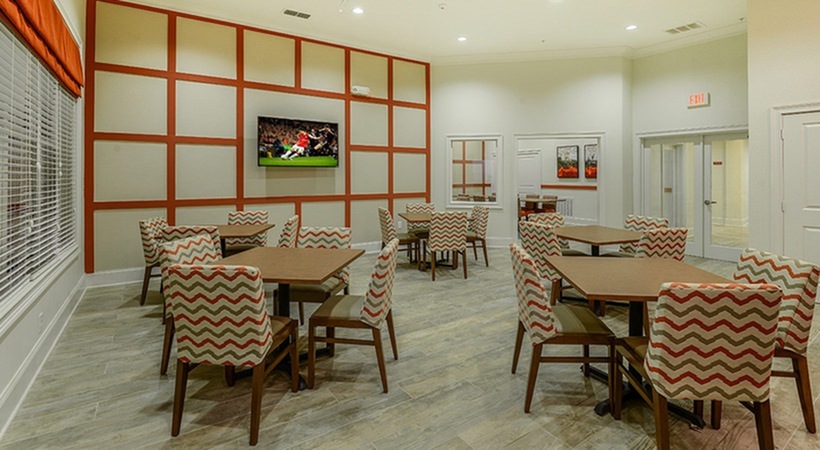 Monterey Pointe, interior, dining hall, tables and chairs, large window, tv, high ceiling, tans and reds for colors