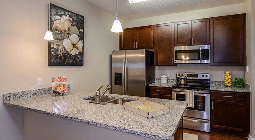 Monterey Pointe, interior, kitchen, peninsula island with double sink, dark cabinets, breakfast bar counter, stainless steel appliances, refrigerator, microwave, stove/oven