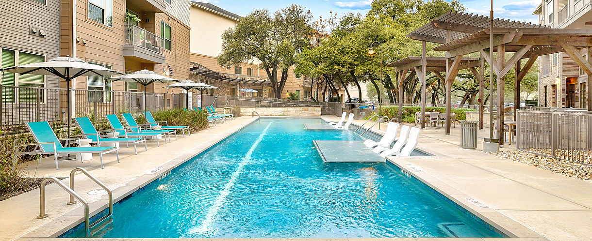Chic apartment community with a stunning outdoor pool, luxurious lounge chairs, and elegant poolside canopies.