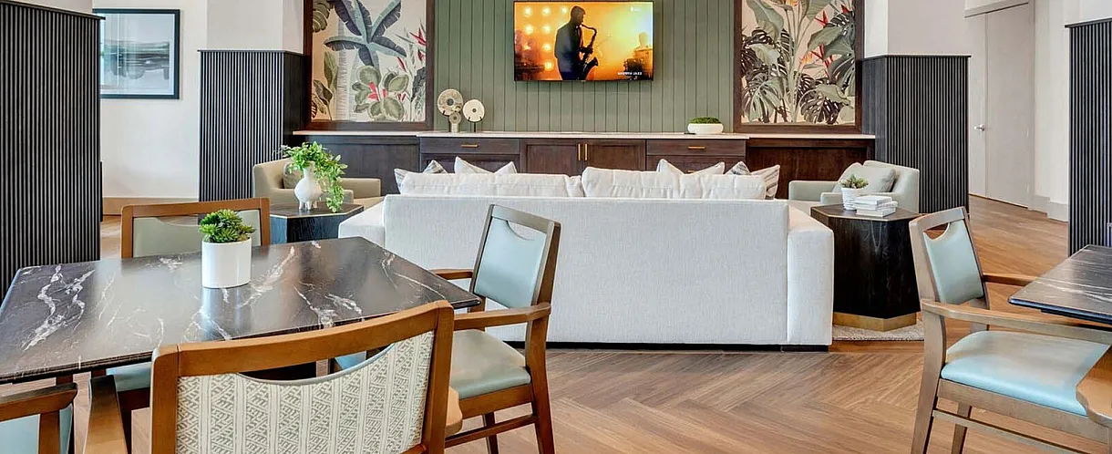 Elegant and spacious living area with modern decor, featuring comfortable seating, a large TV, stylish wooden flooring, and soft lighting.