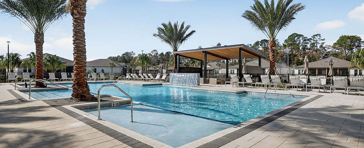 Luxurious outdoor swimming pool area with palm trees and modern lounge chairs, perfect for relaxation and leisure.