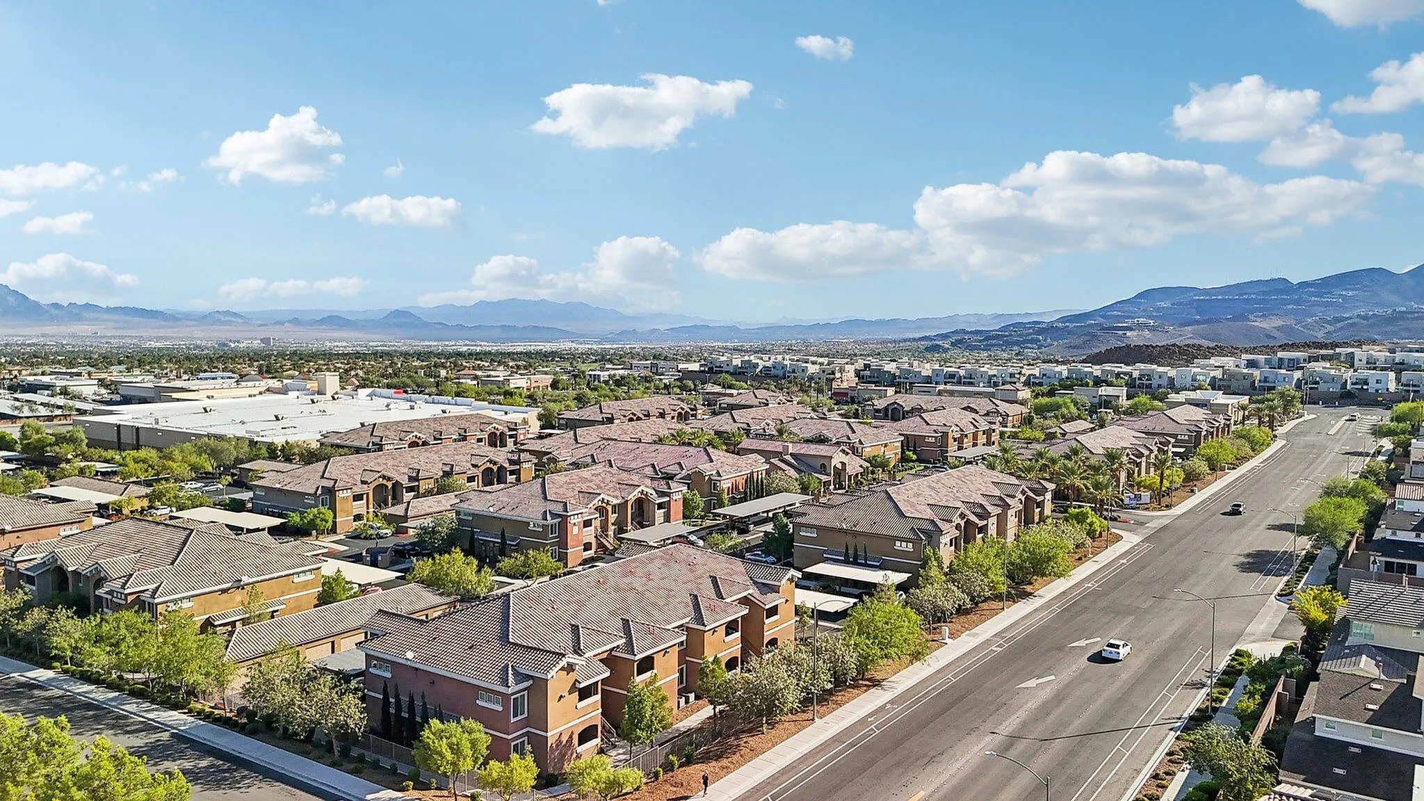 Scenic aerial view of a vibrant residential neighborhood surrounded by lush greenery and set against stunning mountain vistas.