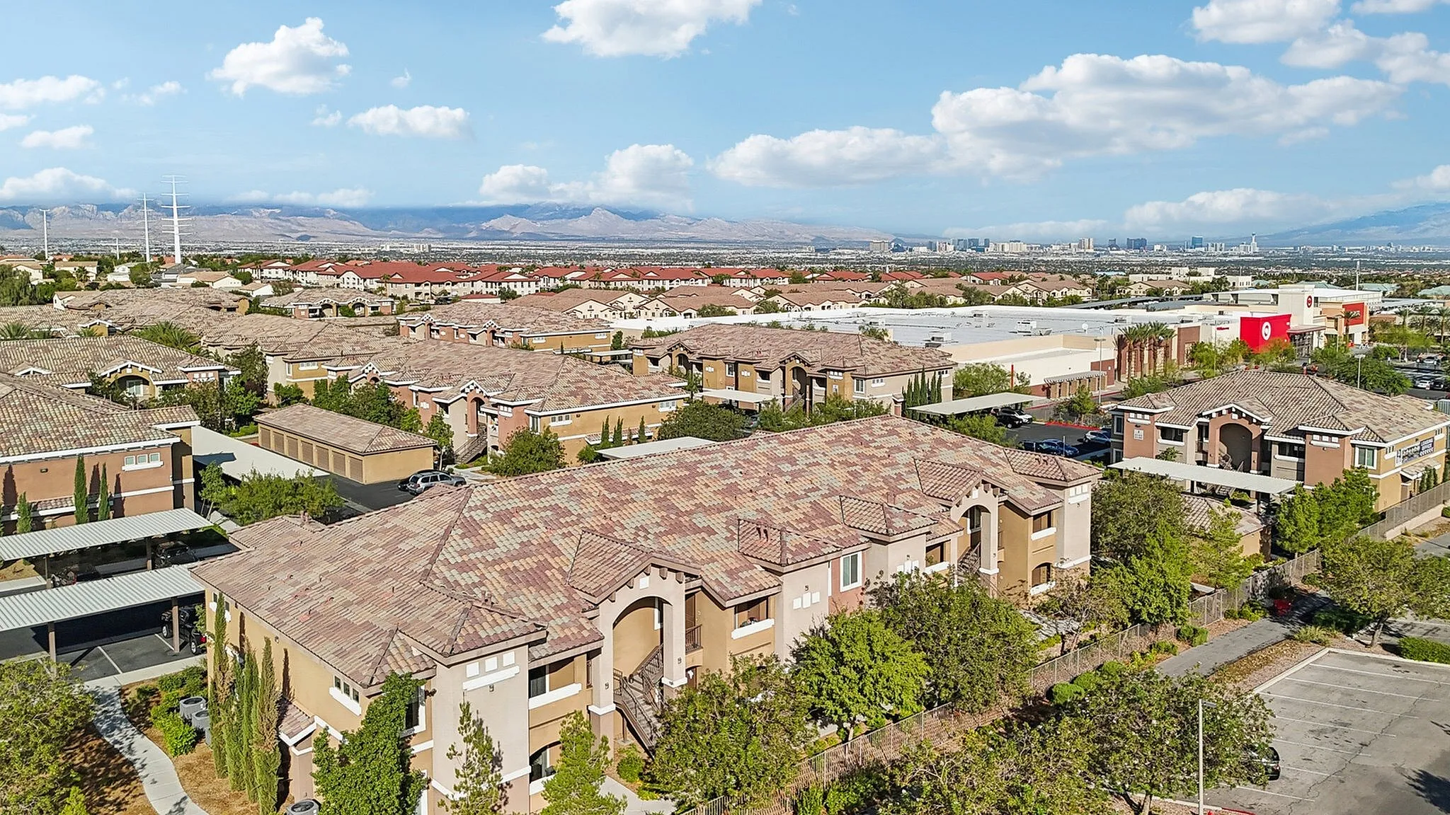 Scenic aerial view of a vibrant residential community with Mediterranean-style architecture, lush greenery, and mountain vistas in the background.