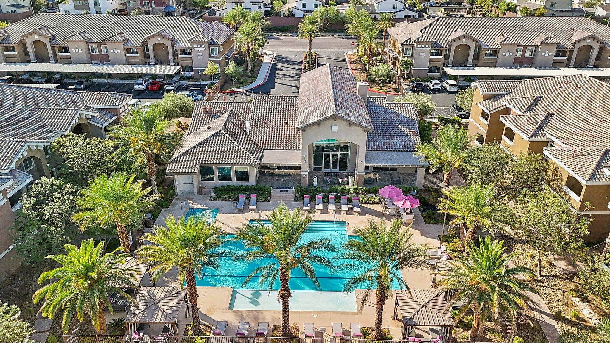 Luxurious apartment complex with a sparkling swimming pool, surrounded by lush palm trees and modern architecture, offering a resort-style living experience.