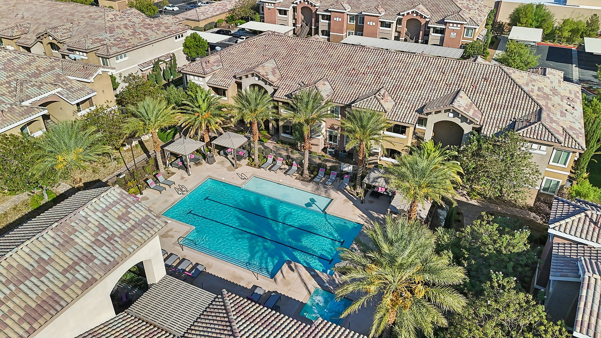 Luxurious apartment complex with a sparkling swimming pool, surrounded by palm trees and stylish buildings, offering a resort-like living experience.