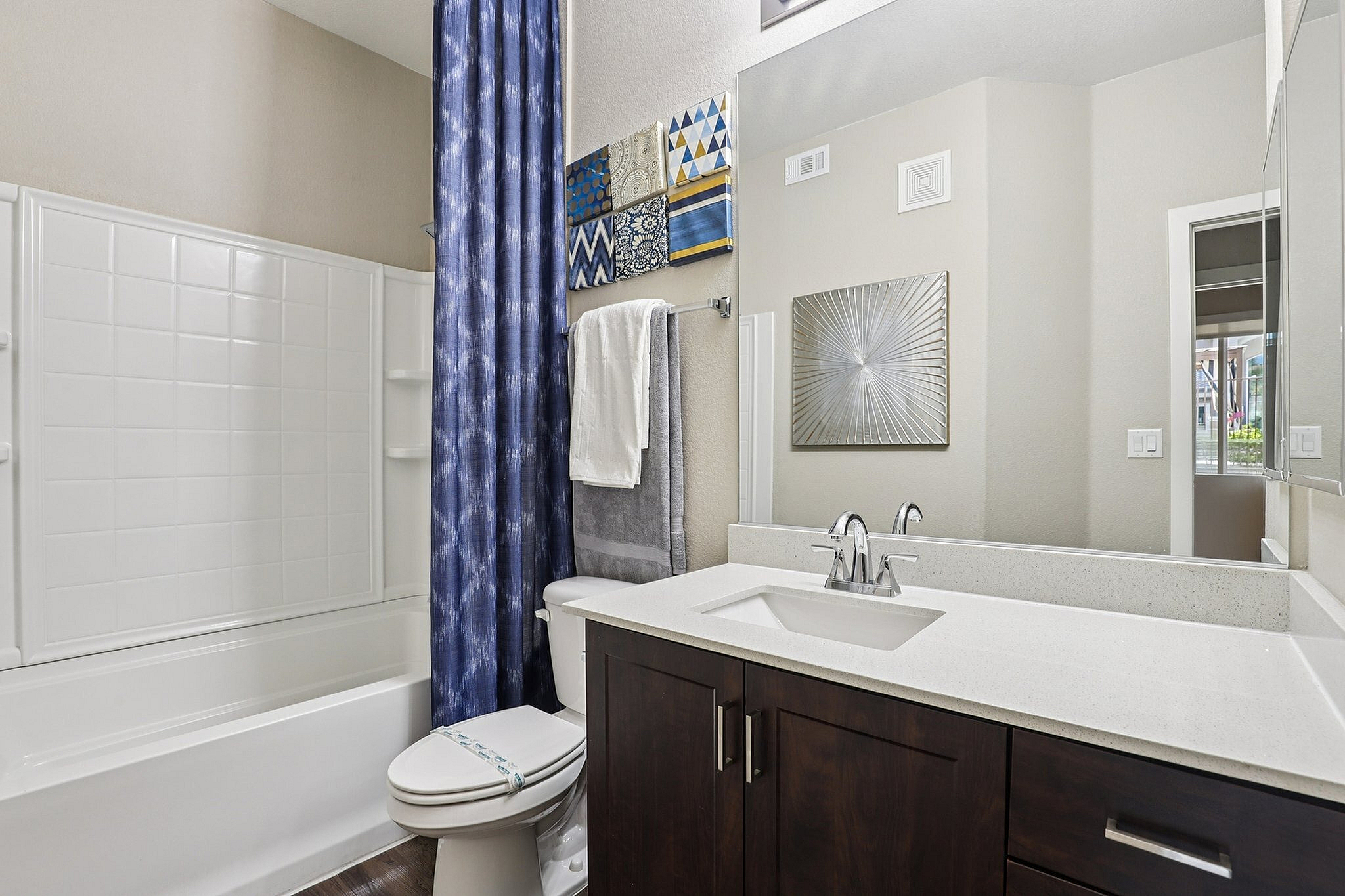 Modern bathroom featuring sleek dark wood cabinetry, a stylish vanity with a polished sink, and an elegant blue shower curtain adding a touch of luxury.