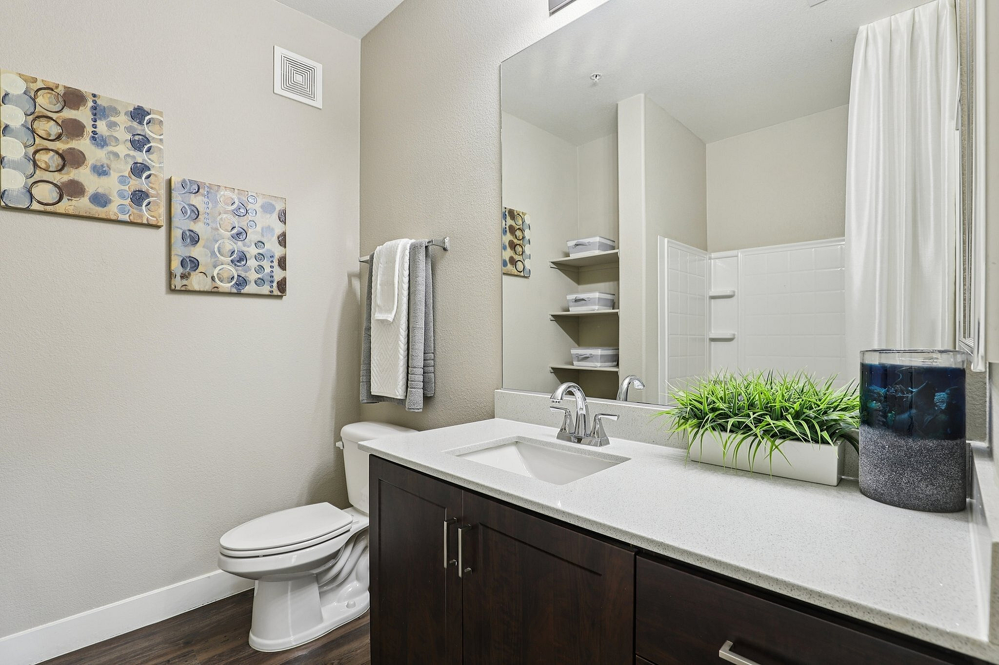 Modern bathroom with elegant decor, featuring a sleek vanity, vibrant green plant, and stylish artwork.