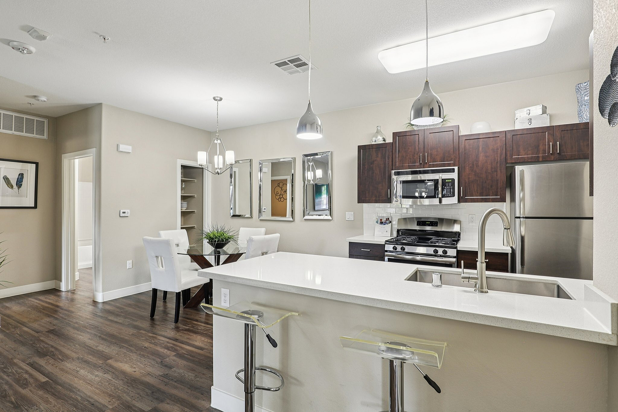 Elegant open-plan kitchen and dining area with modern fixtures, rich wood cabinetry, and sleek stainless steel appliances.