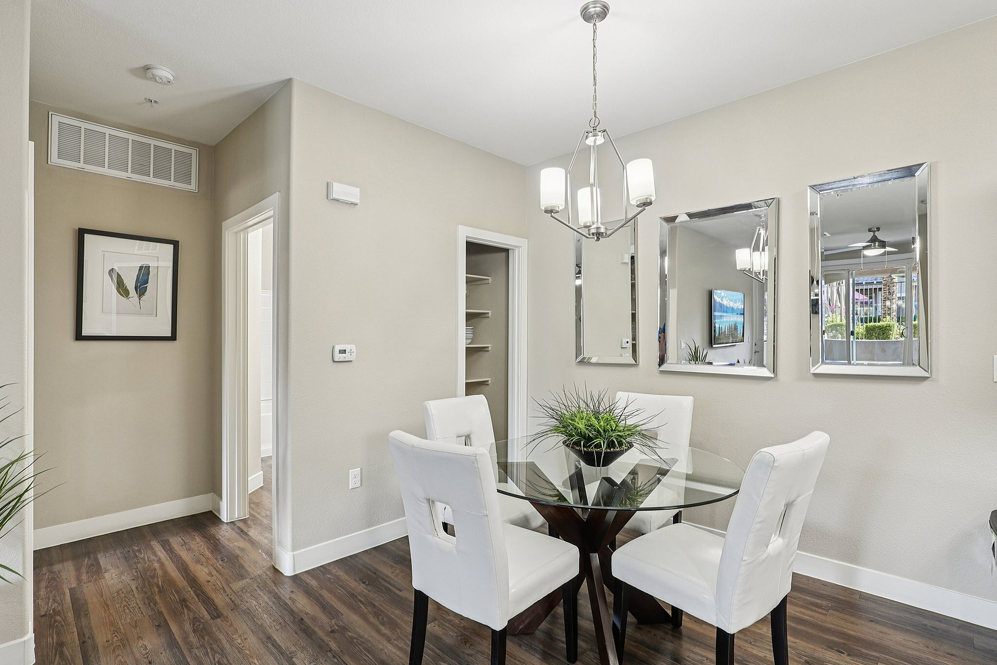 Elegant dining area with a stylish glass table, white cushioned chairs, and modern lighting, perfect for intimate gatherings.